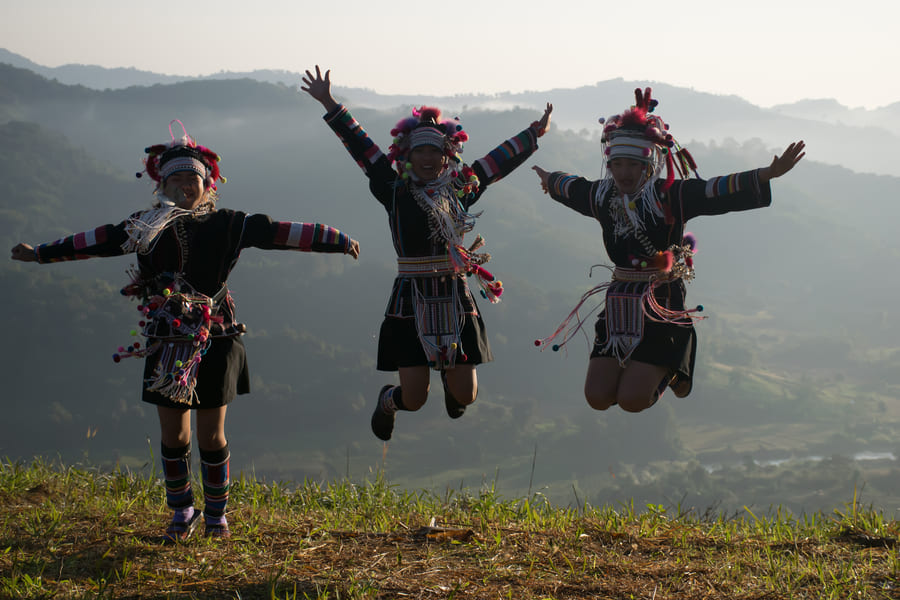 akha, personas locales brincando y disfrutando un paisaje en china